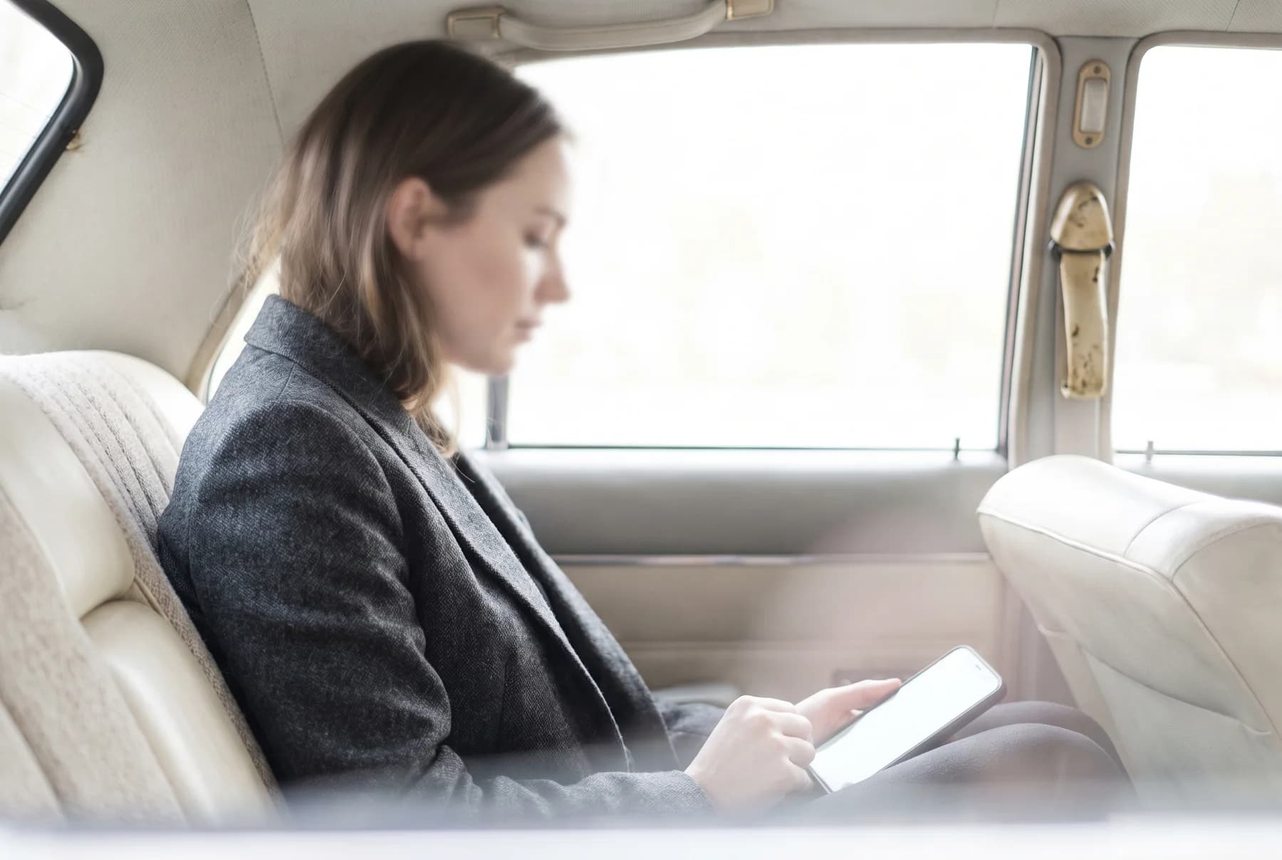A passenger working quietly in the back of a car.
